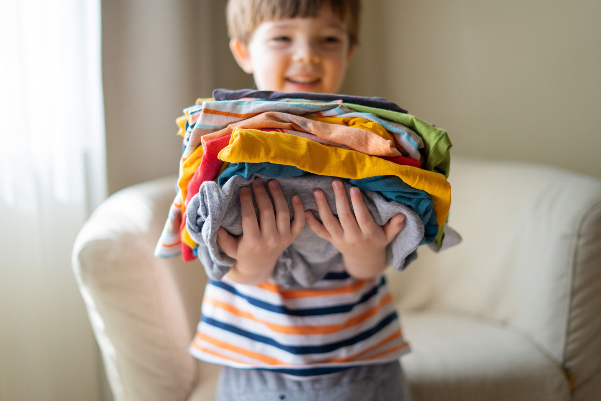 Child holding a pile of folded clothing.